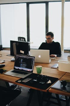 pexels-photo-2102416-2102416 A web developer working on code in a modern office setting with multiple devices.